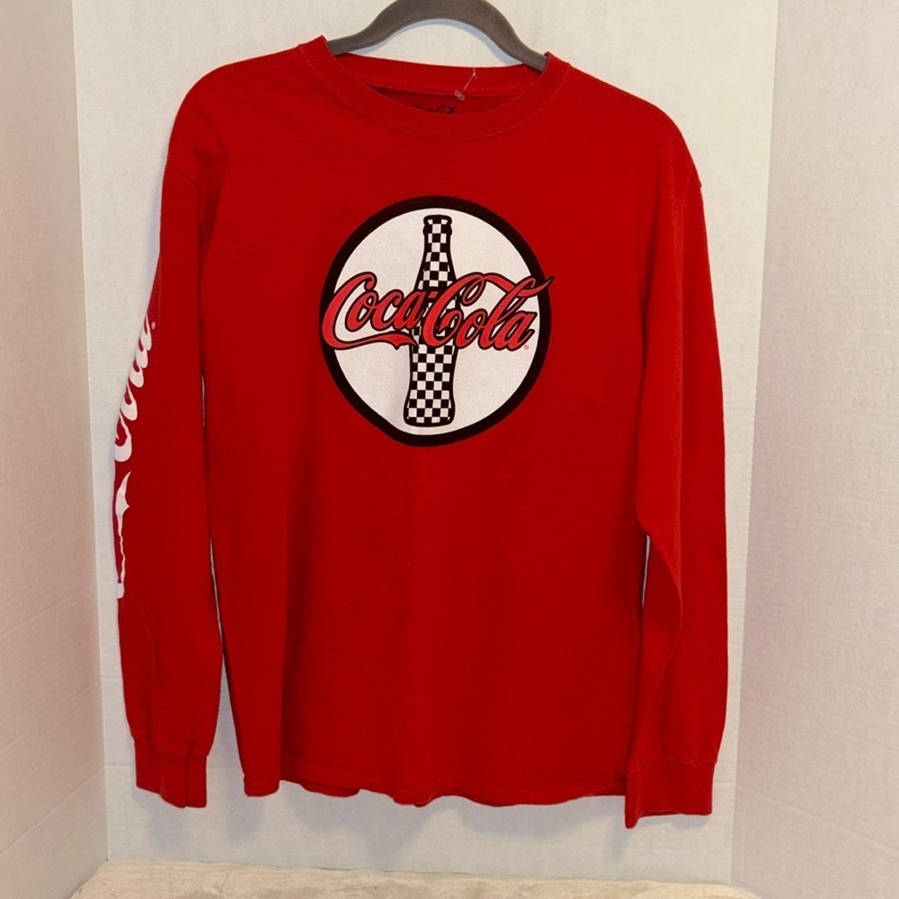 COCA COLA RED LONG SLEEVE TEE SHIRT
WITH GRAPHIC DESIGN ON FRONT SIZE MEDIUM